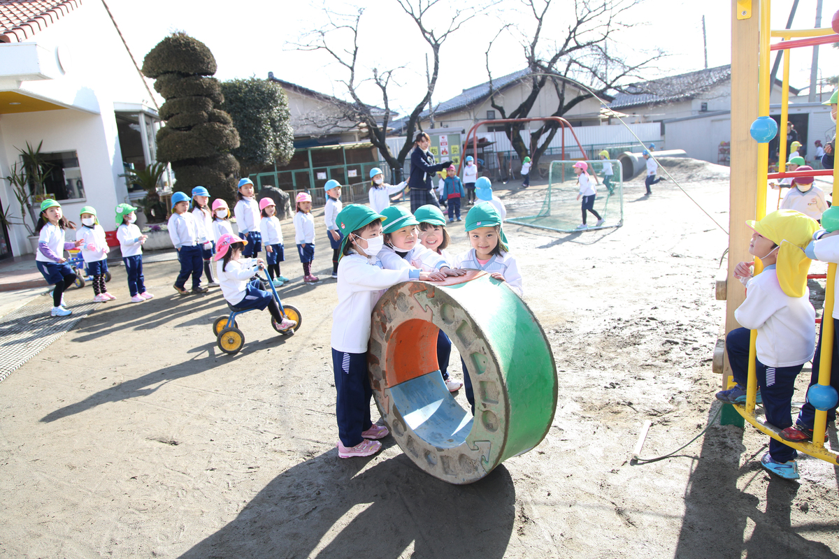 4人の女の子の園児達が輪を転がそうとしている様子