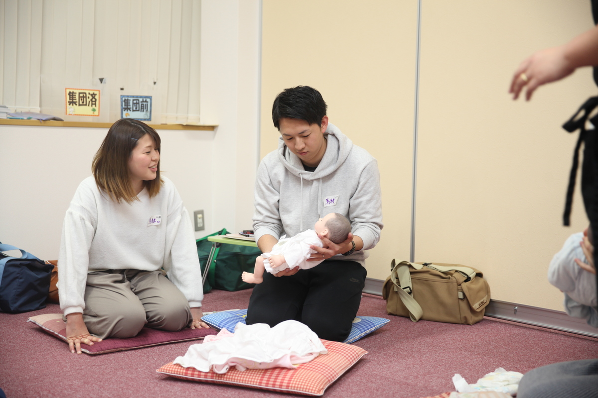 男性が赤ちゃんの人形を抱えている様子