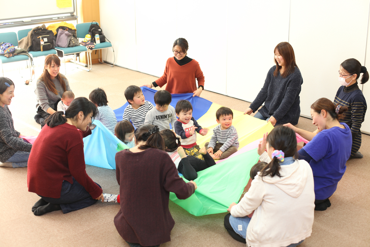 パラシュートを持っているお母さんたちと上に乗っている子ども達