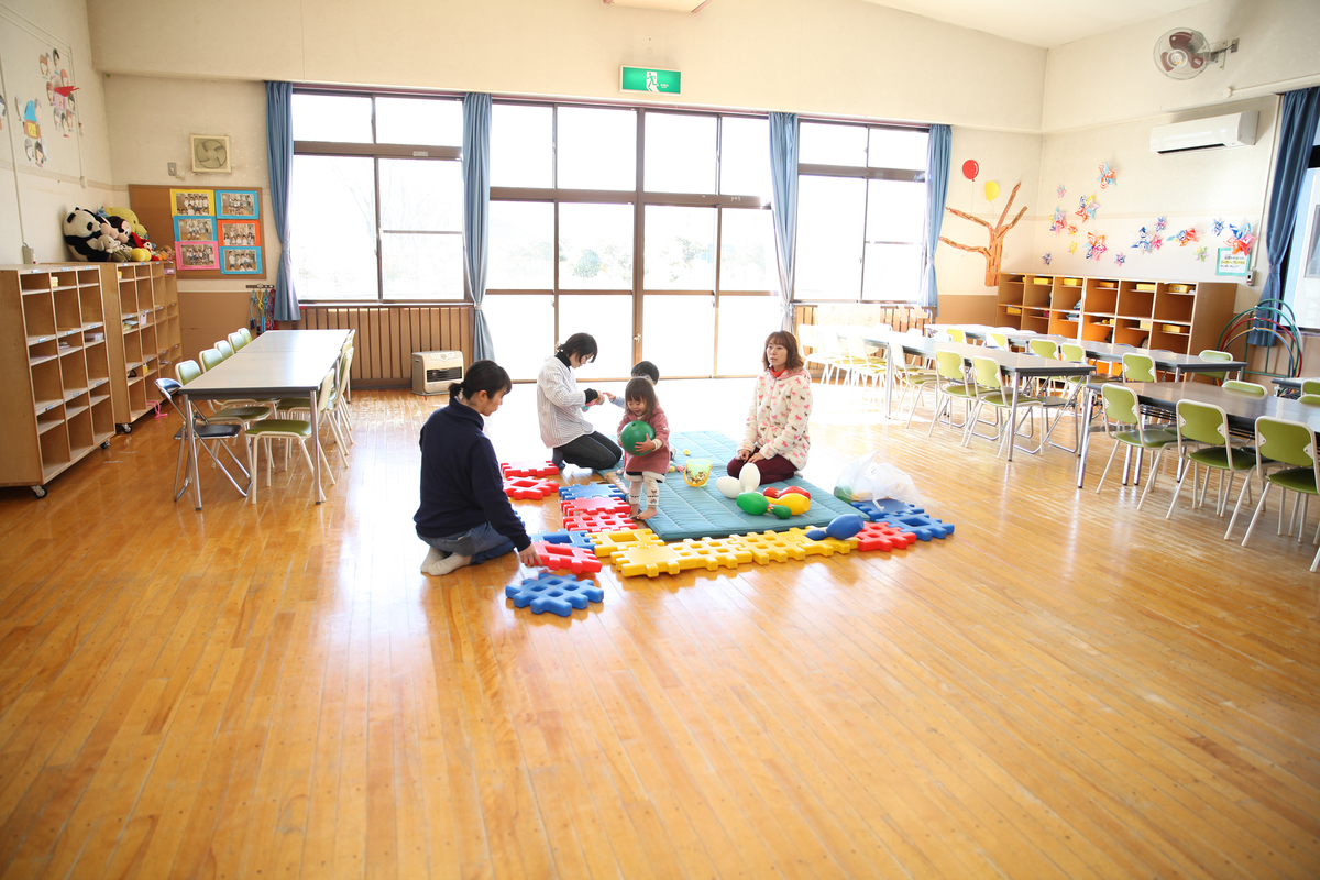 園内でマットの上で子どもと先生達が遊んでいる様子