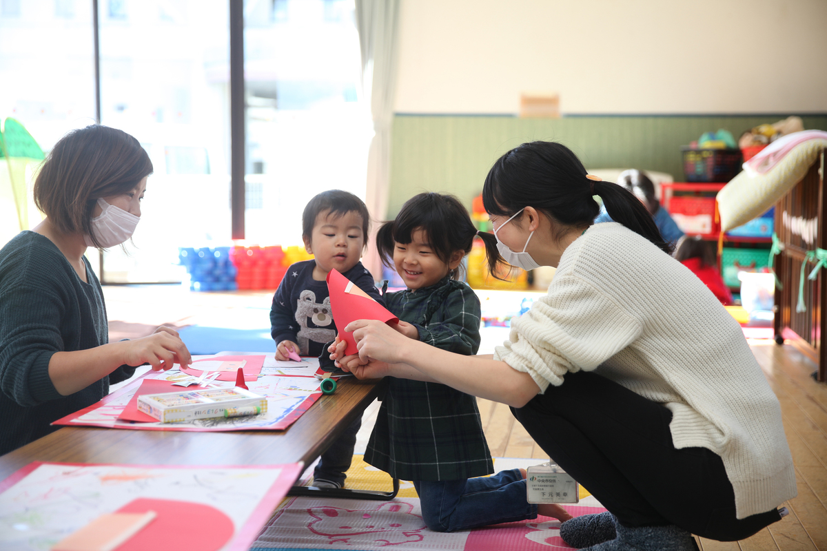 先生と子どもが紙で遊んでいる様子
