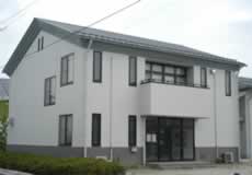 中央市田富防災会館の外観写真。三角屋根の灰色の建物で、正面玄関の二階にはテラスがあります。