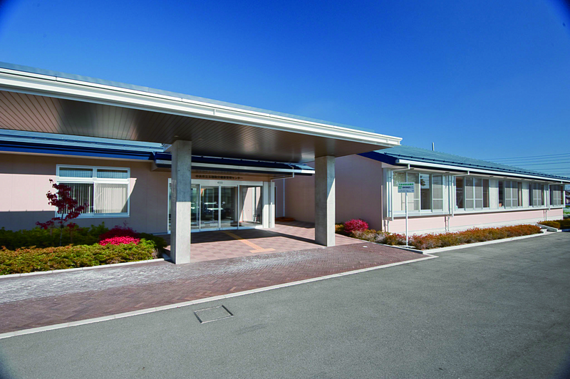 中央市立玉穂勤労健康管理センターの外観写真。青い屋根のあるピンク色の建物です。