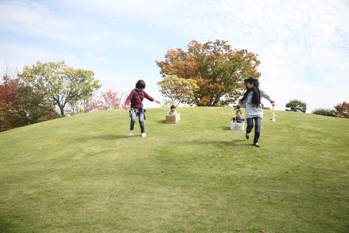 子どもが乗った段ボールについた紐を引っ張るお母さんたち