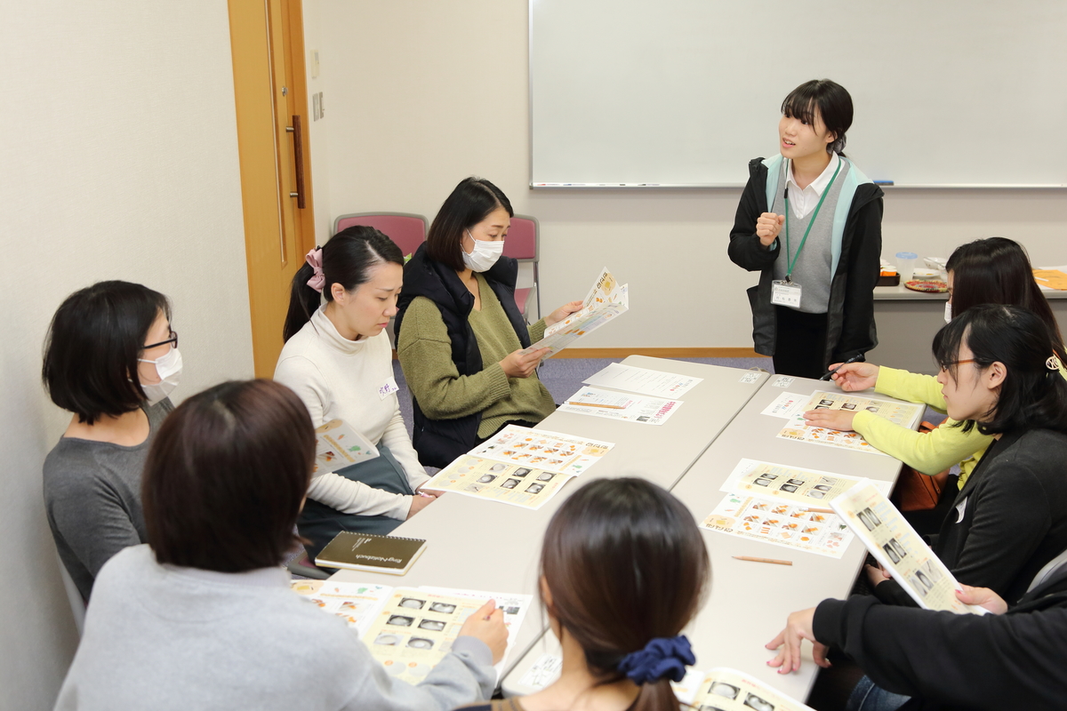 前に立っている女性が座っている女性達に話している様子