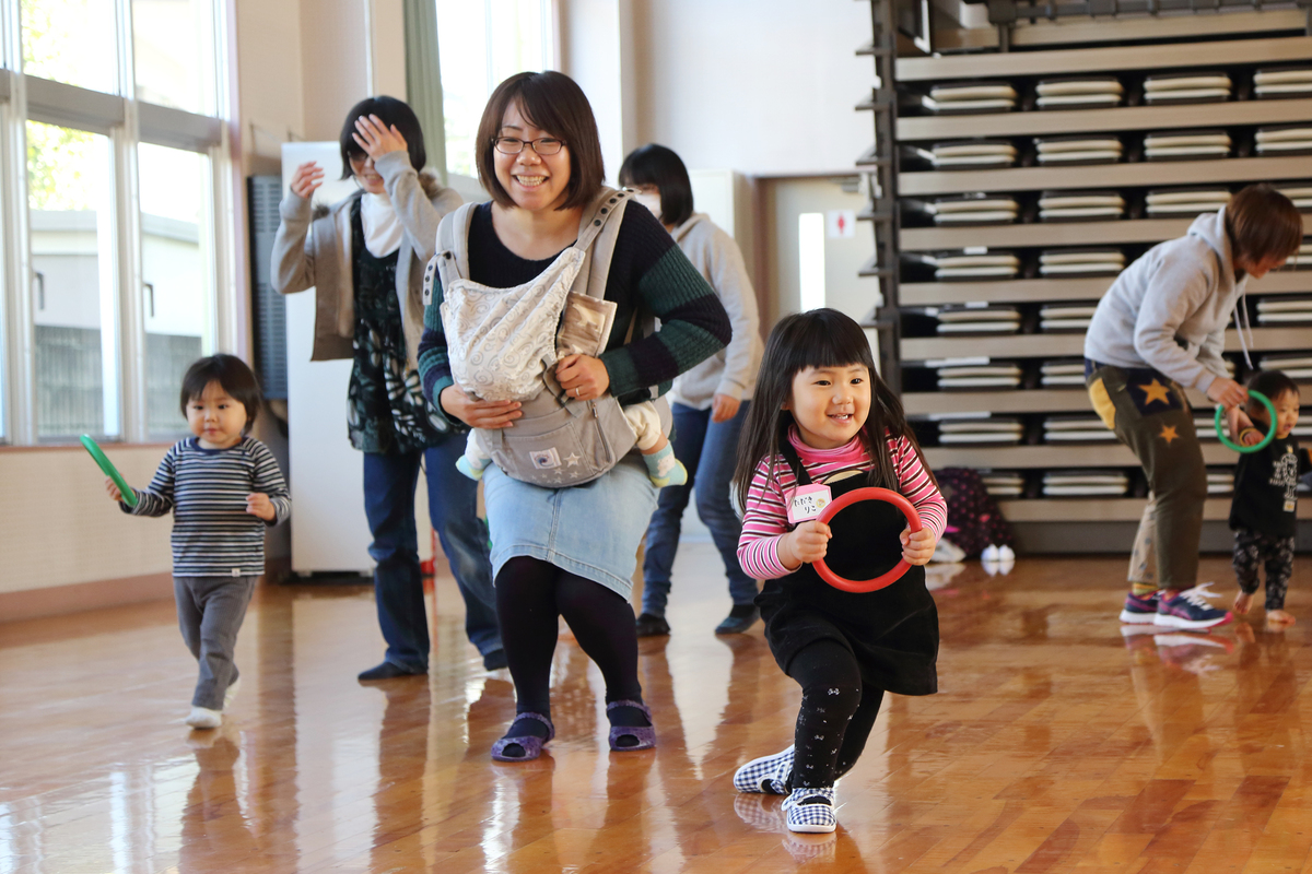 わっかを両手で持っている子どもやその様子を見守るお母さん