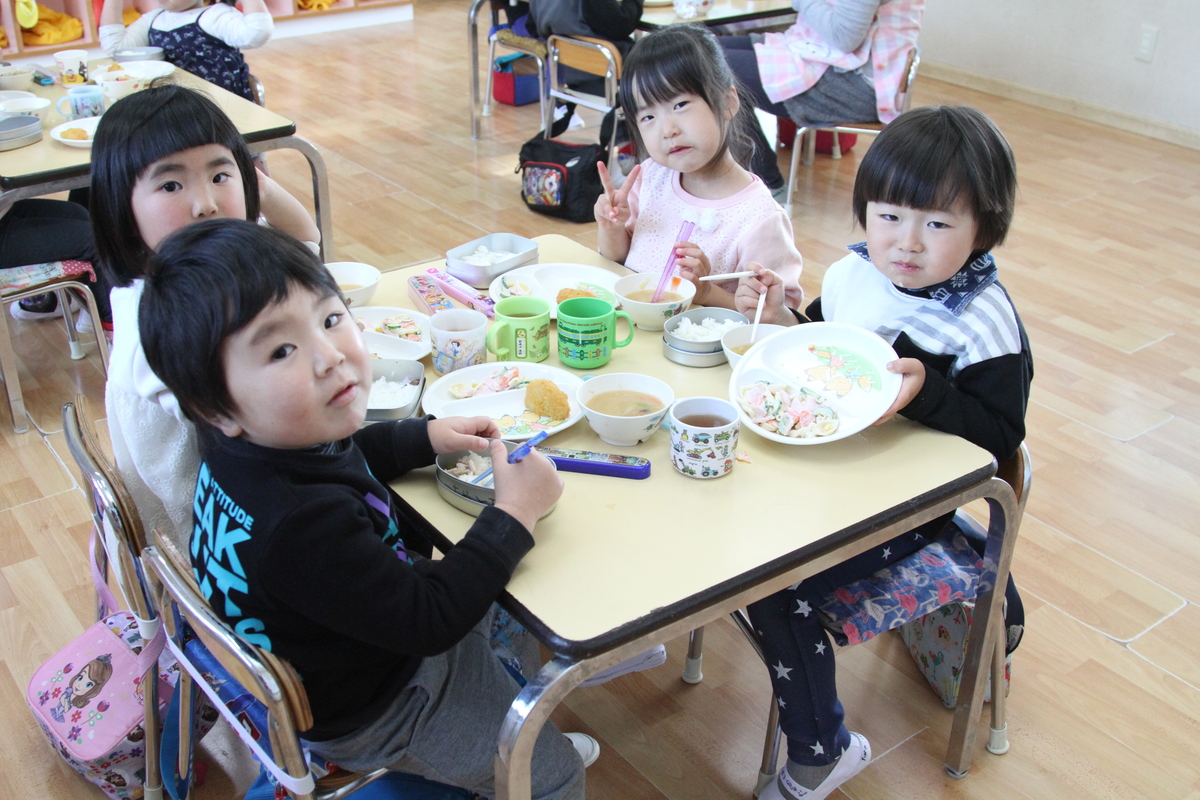 4人の園児達が1つのテーブルに集まってご飯を食べている様子