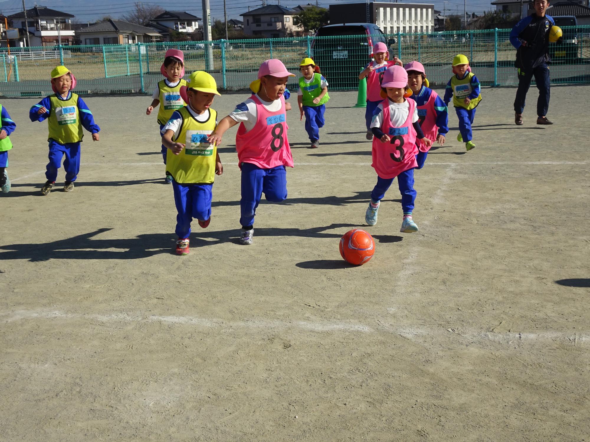 ピンクチームと黄色チームに分かれてサッカーをする子どもたち