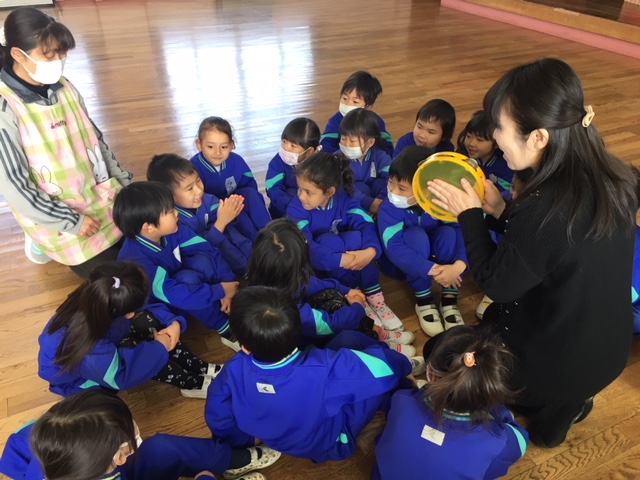 講師を囲むように座りリズムに合わせて返事をする子どもたち