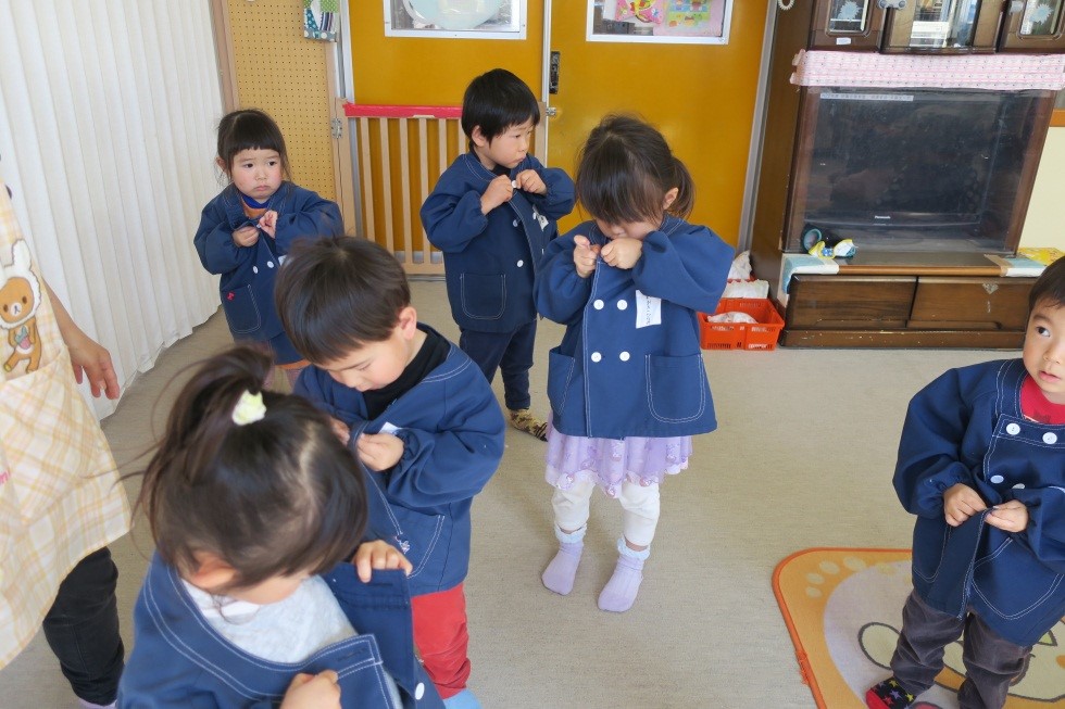 年少組に向けて園服のボタンかけの練習をする子どもたち