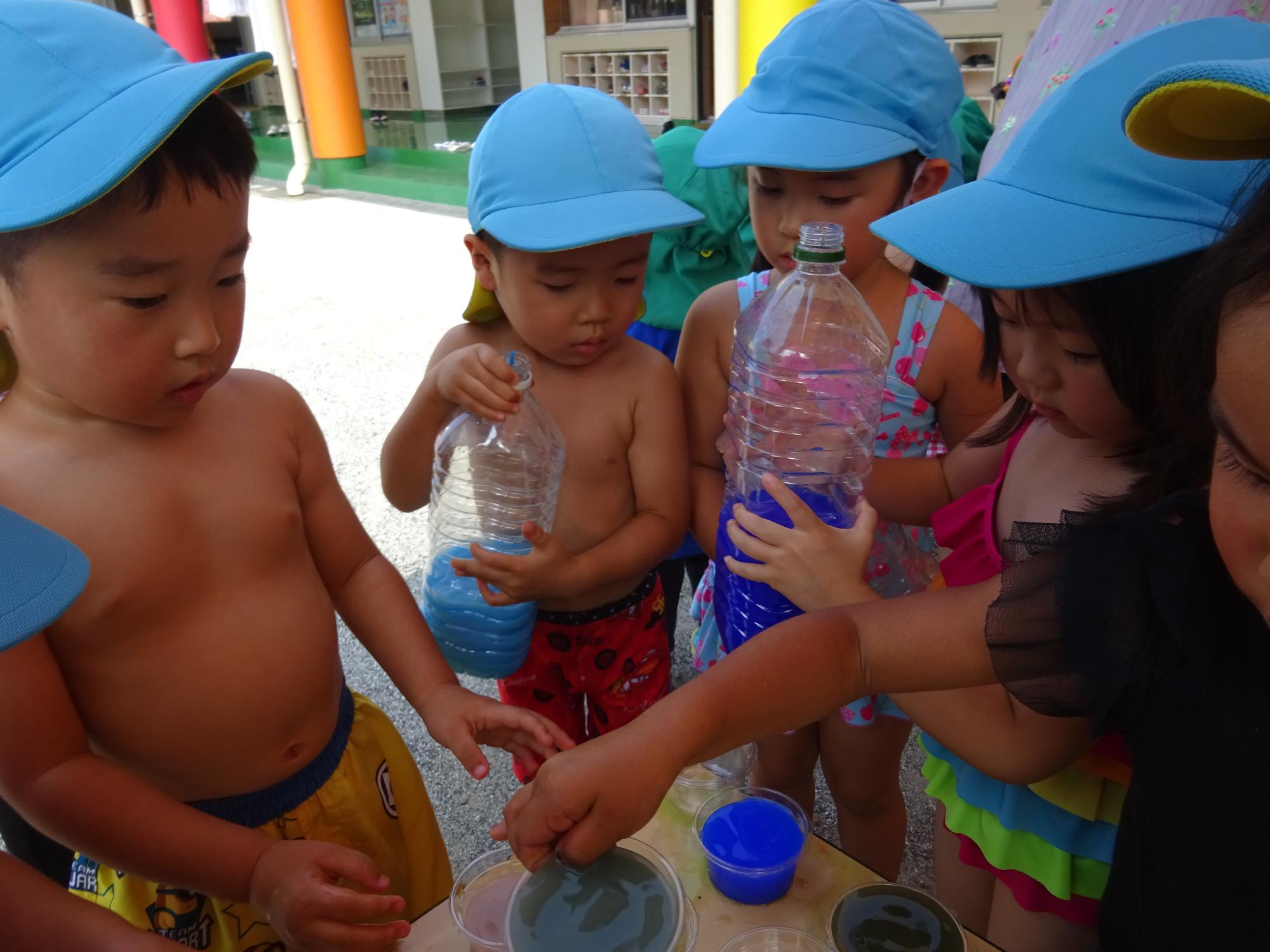 プラスチック容器に色水を入れて遊ぶ年少児