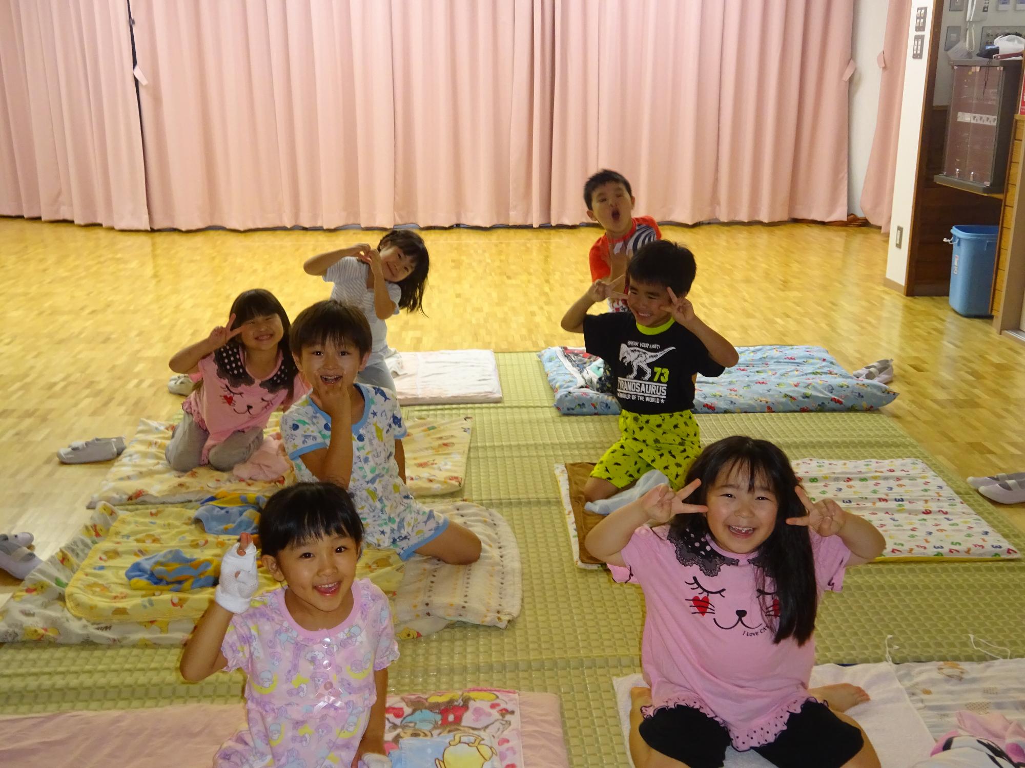 遊戯室で布団を敷き寝る準備をする5歳児の子どもたち