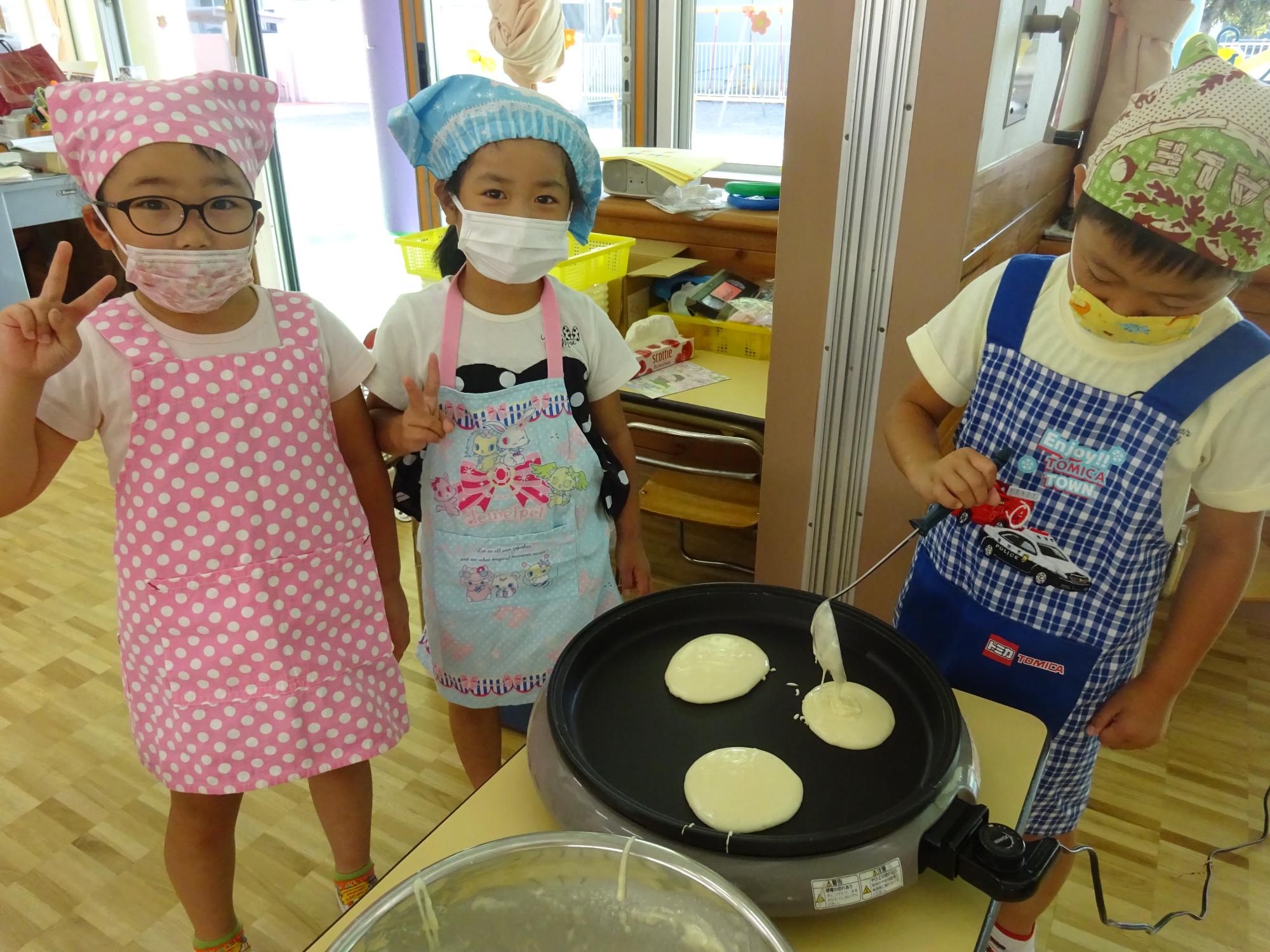 ホットプレートにホットケーキの生地を流す年長児たち