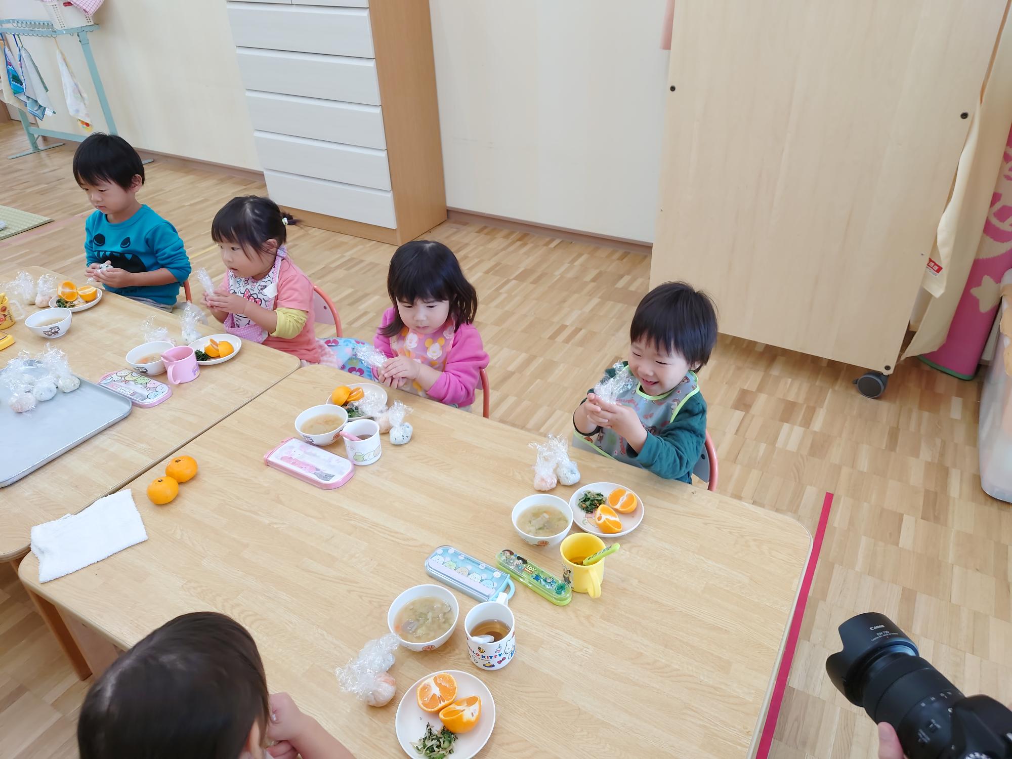 ラップで包まれたご飯を握る2歳児の子どもたち