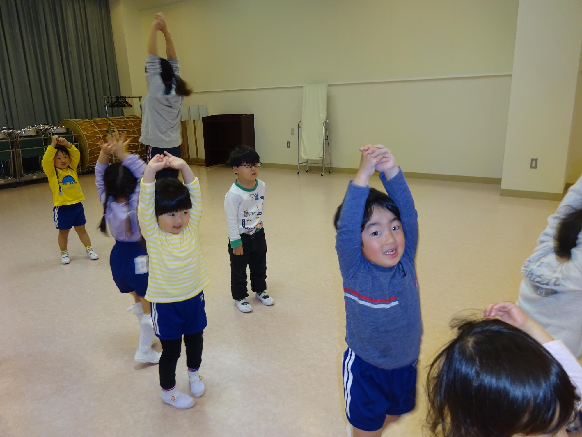 体操教室で大きく背伸びをして笑う年少児