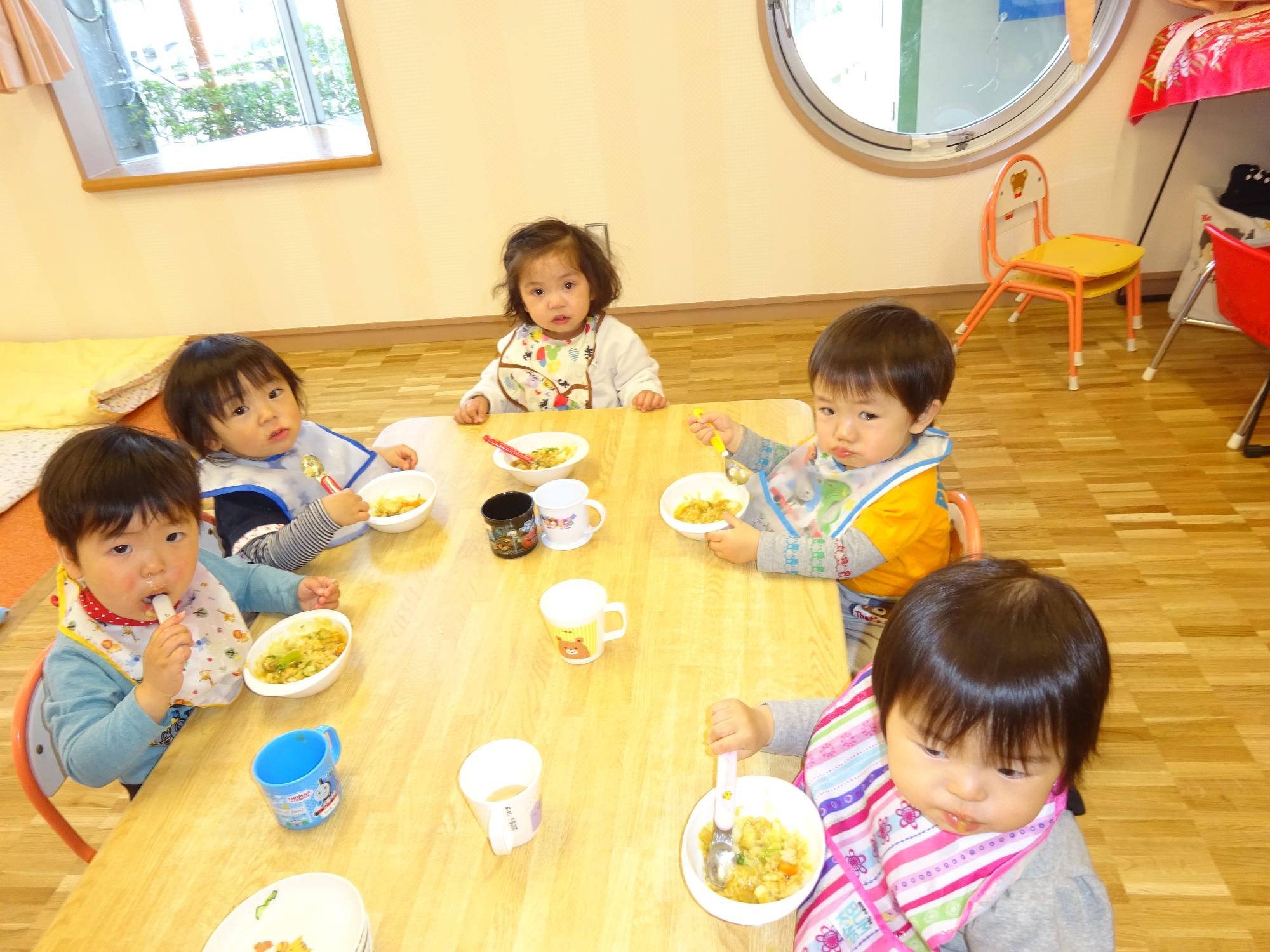 自分でスプーンを持ち、カレーを食べる1歳児