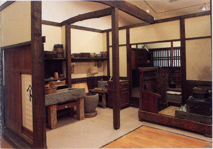 郷土資料展示室の写真（1）。古い時代の木造の生活空間を再現したもので、いろりや窯、臼などの物品が当時さながらに配置されています。